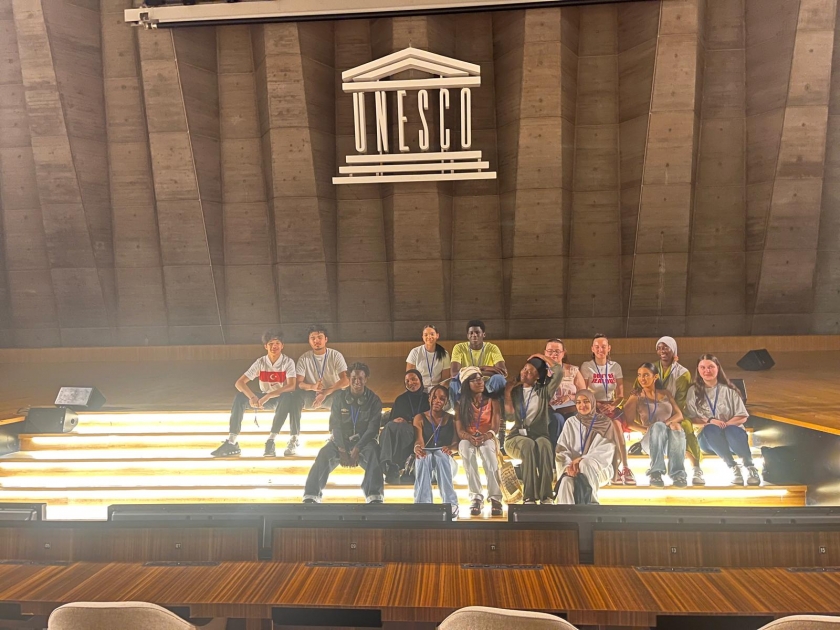 les jeunes assis devant le logo de l'UNESCO