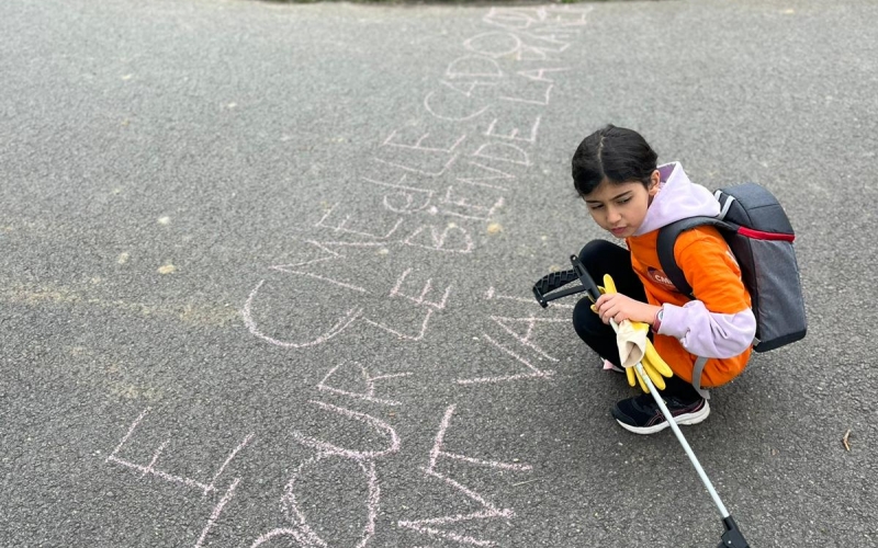 Une enfants du Conseil des Enfants écrit un message de sensibilisation au sol avec une craie