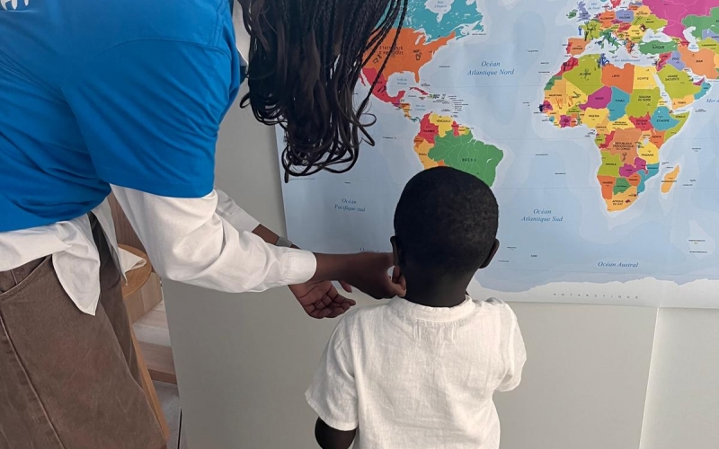 une jeune donne un tampon a un enfant pour qu'il indique sur une carte du monde d'où viennent sa nourriture et musique préférées